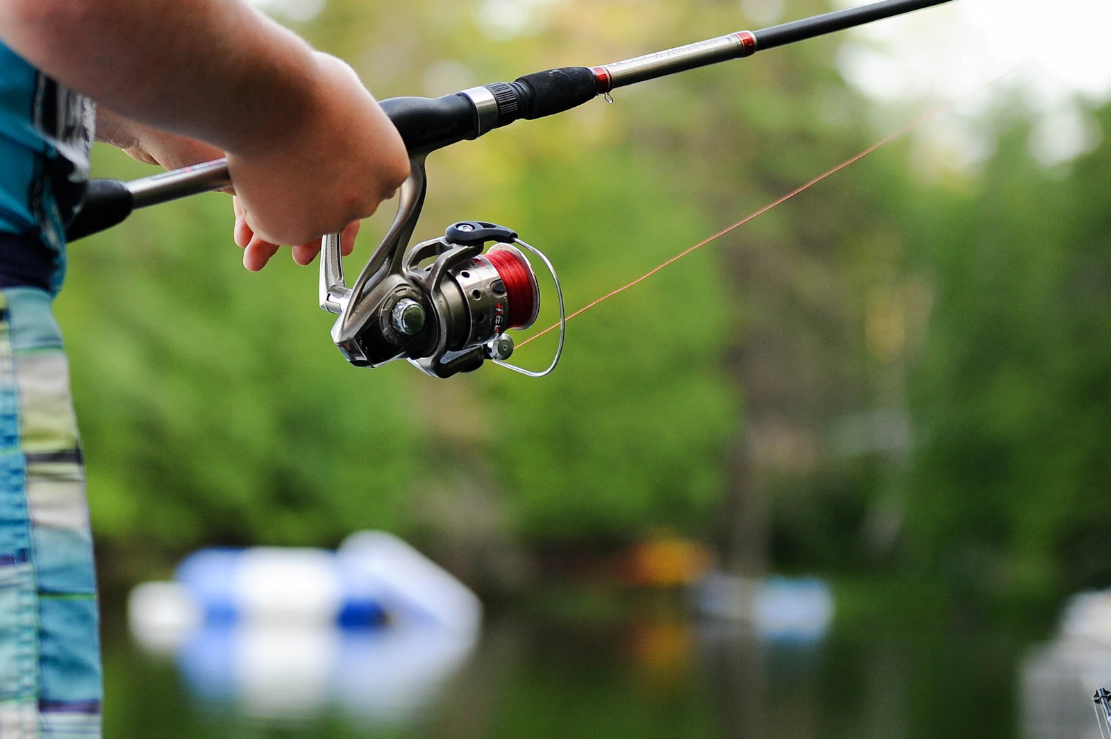 An angler holding a spinning reel and fishing rod